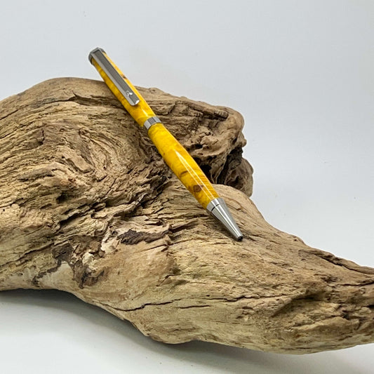 Handcrafted Box elder wood pen dyed yellow setting on driftwood