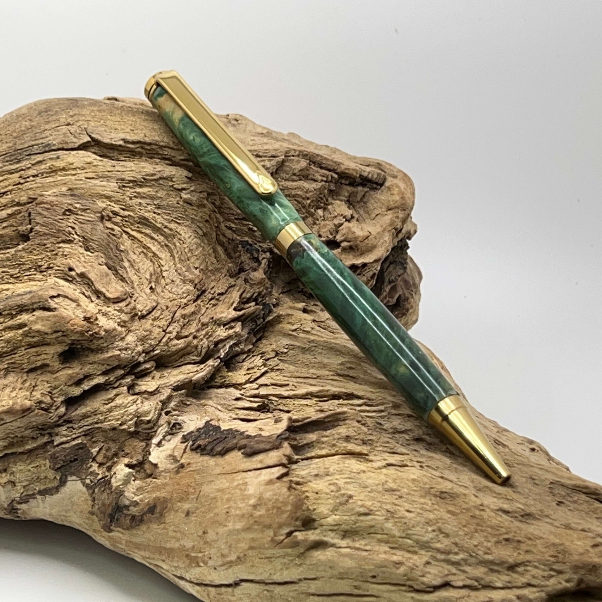 Handcrafted Box elder wood pen dyed green setting on driftwood