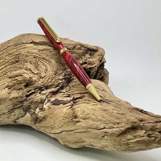 Handcrafted Box elder wood pen dyed red setting on driftwood