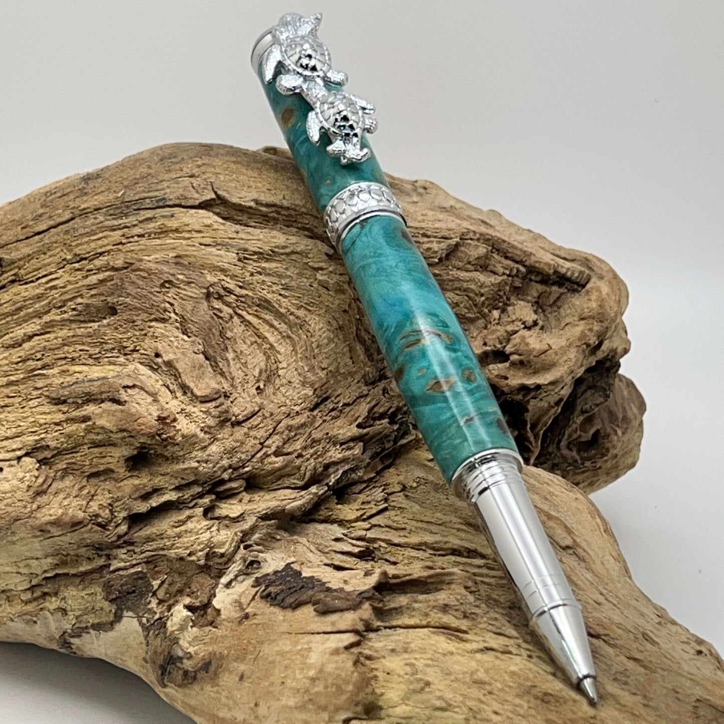 Handcrafted Box elder wood pen dyed turquoise with turtle cap setting on driftwood