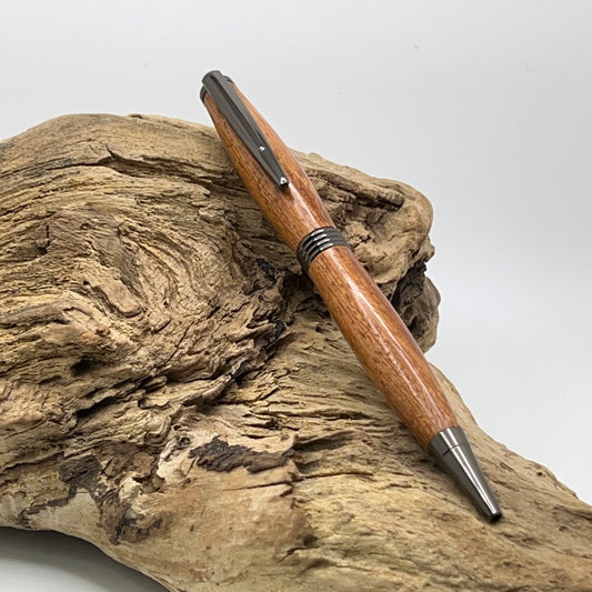 Handcrafted Angelim Pedra Wood pen with gunmetal hardware setting on driftwood