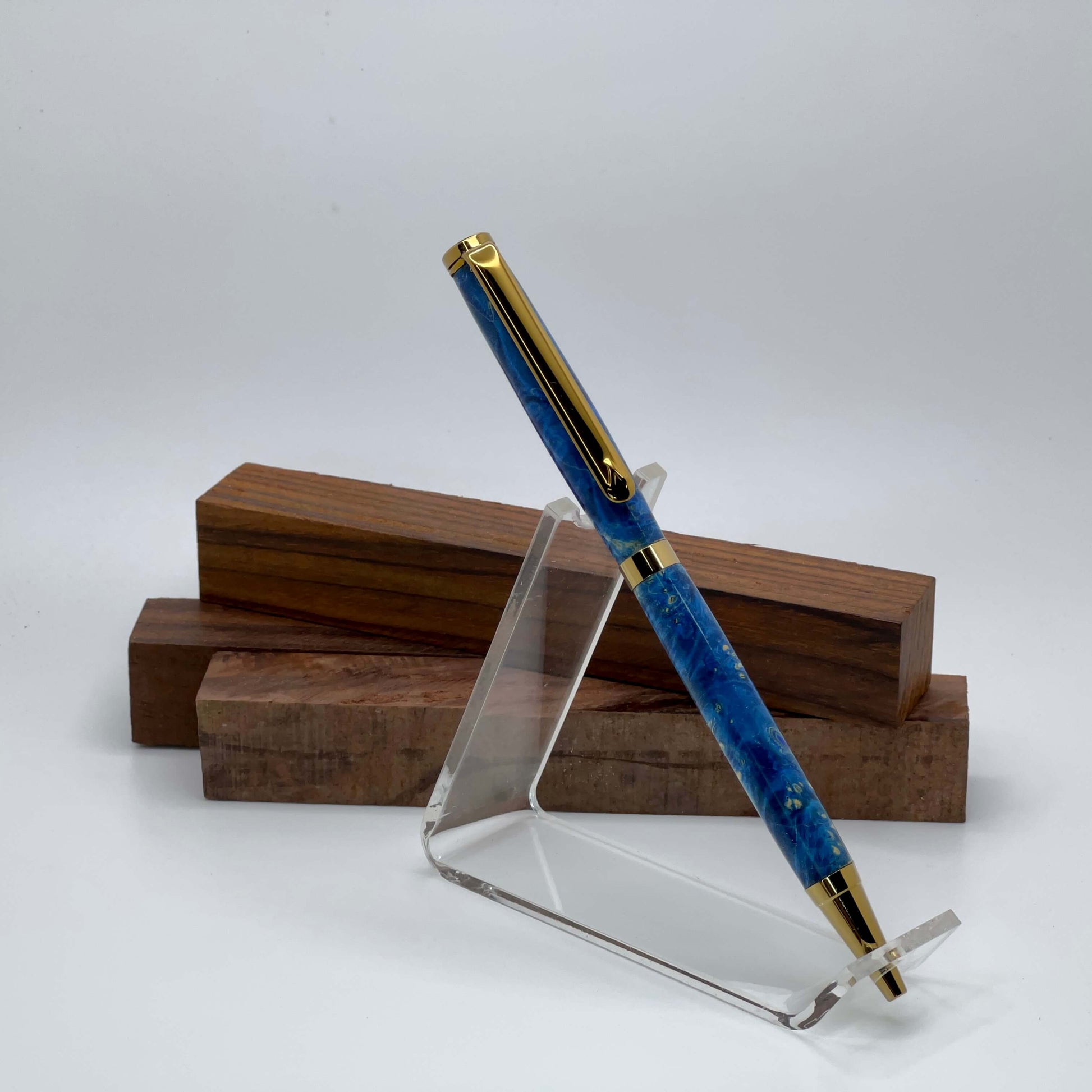 Handcrafted Box elder wood pen dyed blue setting on driftwood